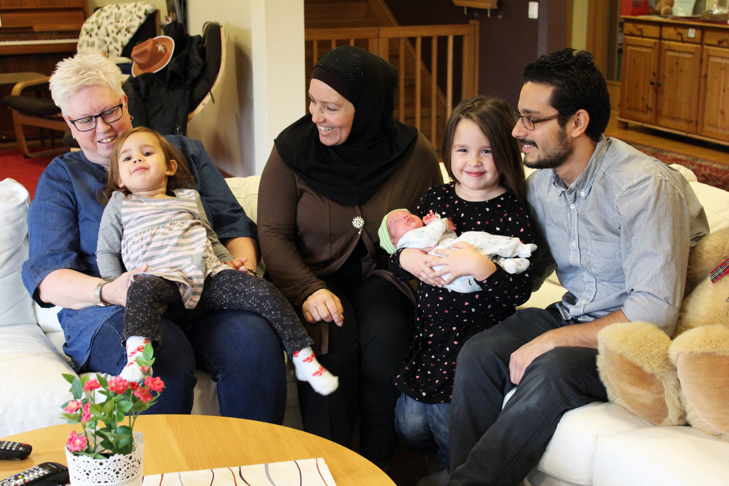 En pappa, tre barn, en farmor och en mormor sitter i en soffa på Ronald McDonald Hus Linköping